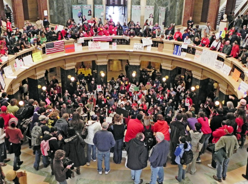 Union workers, teachers and other protesters showed up for weeks in 2011 at Wisconsin’s Capitol in Madison to protest Act 10, which weakened public sector unions. (Richard Hurd via Flickr, license: CC BY 2.0)
