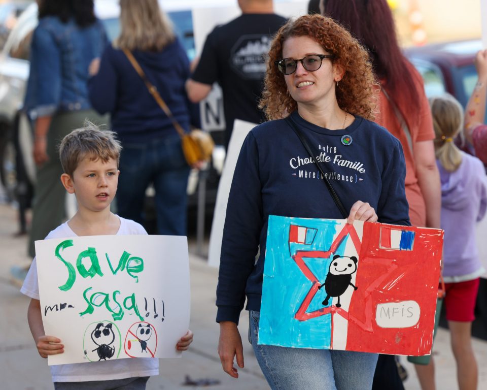 Emily Jalabert walks with her son during a protest against staffing cuts at the Milwaukee French Immersion School. (Photo by Jonathan Aguilar / Milwaukee Neighborhood News Service / CatchLight Local)