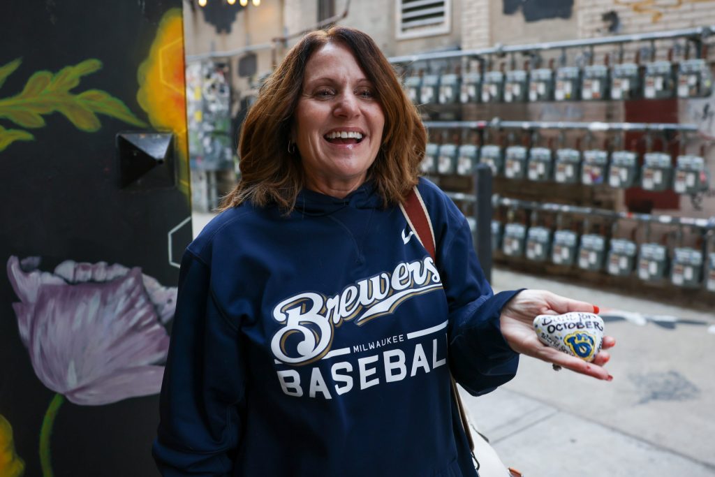 Michelle Gygax holds up a hand-painted rock, a part of her ongoing project titled Sam’s Rocks WI, on Oct. 21. Gygax leaves her hand-painted rocks at different locations in memory of her late father, Sam, who enjoyed sharing kind messages and words of encouragement. (Photo by Jonathan Aguilar / Milwaukee Neighborhood News Service / CatchLight Local)
