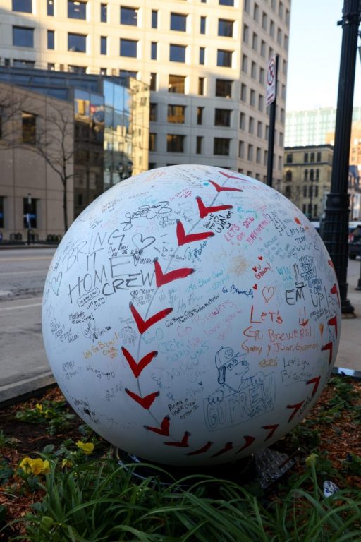 A baseball sculpture covered in drawings and messages from Milwaukee Brewers fans sits in front of the Pfister Hotel.