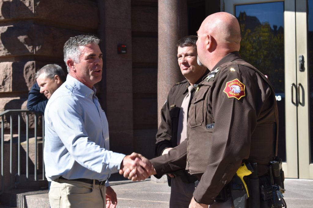 Republican U.S. Rep. Tony Wied, left, shakes hands with a member of law enforcement on Oct. 5, 2026. Joe Schulz/WPR