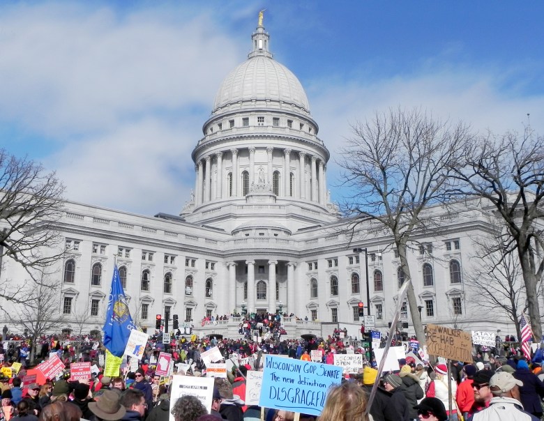 After Gov. Scott Walker unveiled the Wisconsin budget repair bill in February 2011, which sought to end collective bargaining for most public sector unions, thousands of protesters took to the streets of Madison in opposition. Protesters are seen here in front of the Wisconsin State Capitol on March 12, 2011, a day after the bill was passed. (Richard Hurd via Flickr, license: CC BY 2.0)