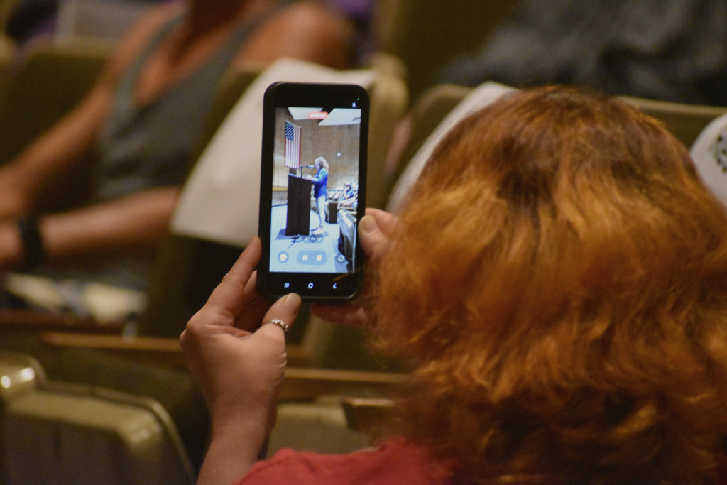 A Wisconsin Rapids woman records a video of multiple locals speaking out against the data center proposal at a city meeting. Avery Martinez/WPR