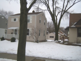 A juvenile Fraxinus, this one planted by the city, will likely escape the pruning disaster that befell its elder cousin. Yet perhaps the Emerald Ash Borer -- or the treatment of that disease -- may cost them both their lives. This view through the grounds of the Larson property, taken from the northeast, includes a glimpse of its garage, constructed in 1956.