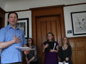 Freund introduces the cast for a series of comic book readings at the opening of his art gallery, Spoilers.