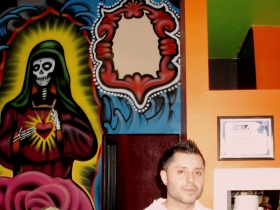 Roman Torrez is backed by part of the Dia de los Muertos mural at Mr. Webo's, as well as the Blue Ribbon Award from Channel 4.