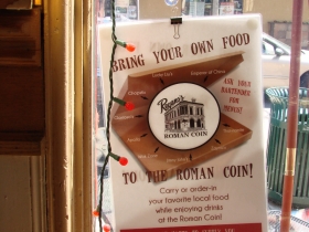 A sign in the window welcomes food from other venues.