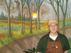 General Manager Chris Kadrich is backed by a mural donated by artist Colleen Drew, visually describing the path veterans take from active service to their return home.