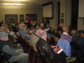 A lecture is about to begin for a packed house at the Grohmann Museum.