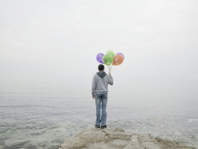 Boy with balloons stays at the seashore in Aqtau, a town created in 1963 as a model socialist city for uranium miners. The mines are now closed; Aqtau is being remodeled as the City of Energy. Kazakhstan. 2013