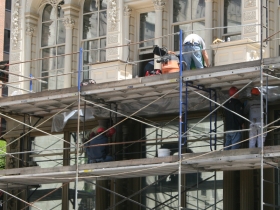 Construction workers putting finishing touches on the Iron Block Building.