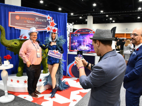 David Caruso Looks On As Guest Takes Photo At His Booth