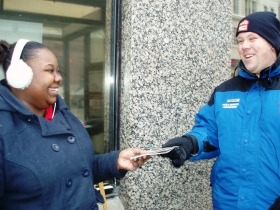 Andrea Brown is happy to receive an information packet from Justin Miller while she waits for a bus on W. Wisconsin Ave. Photo by Peggy Schulz