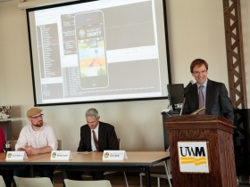 UWM Chancellor Michael Lovell (center) listens as Milwaukee County Executive Chris Abele reacts to the new mobile app created by UWM students for the county. Also pictured is Quinn Madsen (left of Lovell), who is the lead developer at the UWM Mobile Innovation Lab.