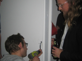 Gallery owner John Riepenhoff (l) steadies the door while an emergency repair is made to the handle, which had seen heavy use as visitors went from the projection room to the sanctuary of the beverage department.