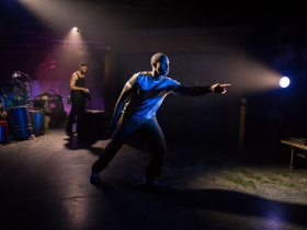 Foreground: Andrew Muwonge as Oshoosi Size, Background: Jahmés Tony Finlayson, Travis A. Knight as Ogun Size