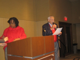 Gene Gilbert introduces Rep. Gwen Moore who is still fussing with her microphone at St. John's on the Lake Monday, December 30th, 2013.
