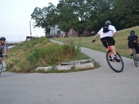 Unicyclist on the Verge of Passing a Rider Uphill