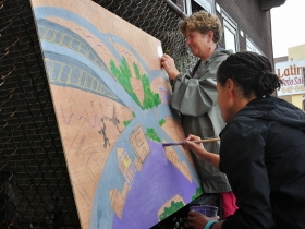 Ciera McKissick (foreground) and Ann Loper (background) paint a Silver City-inspired art piece.