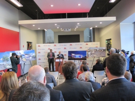 Renderings of the new stage are visible throughout the room