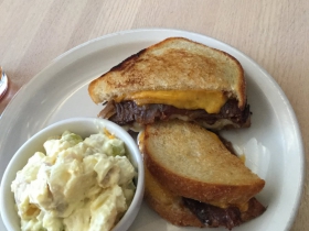 Deluxe grilled cheese with bacon, grilled onions, and tomato jam and potato salad